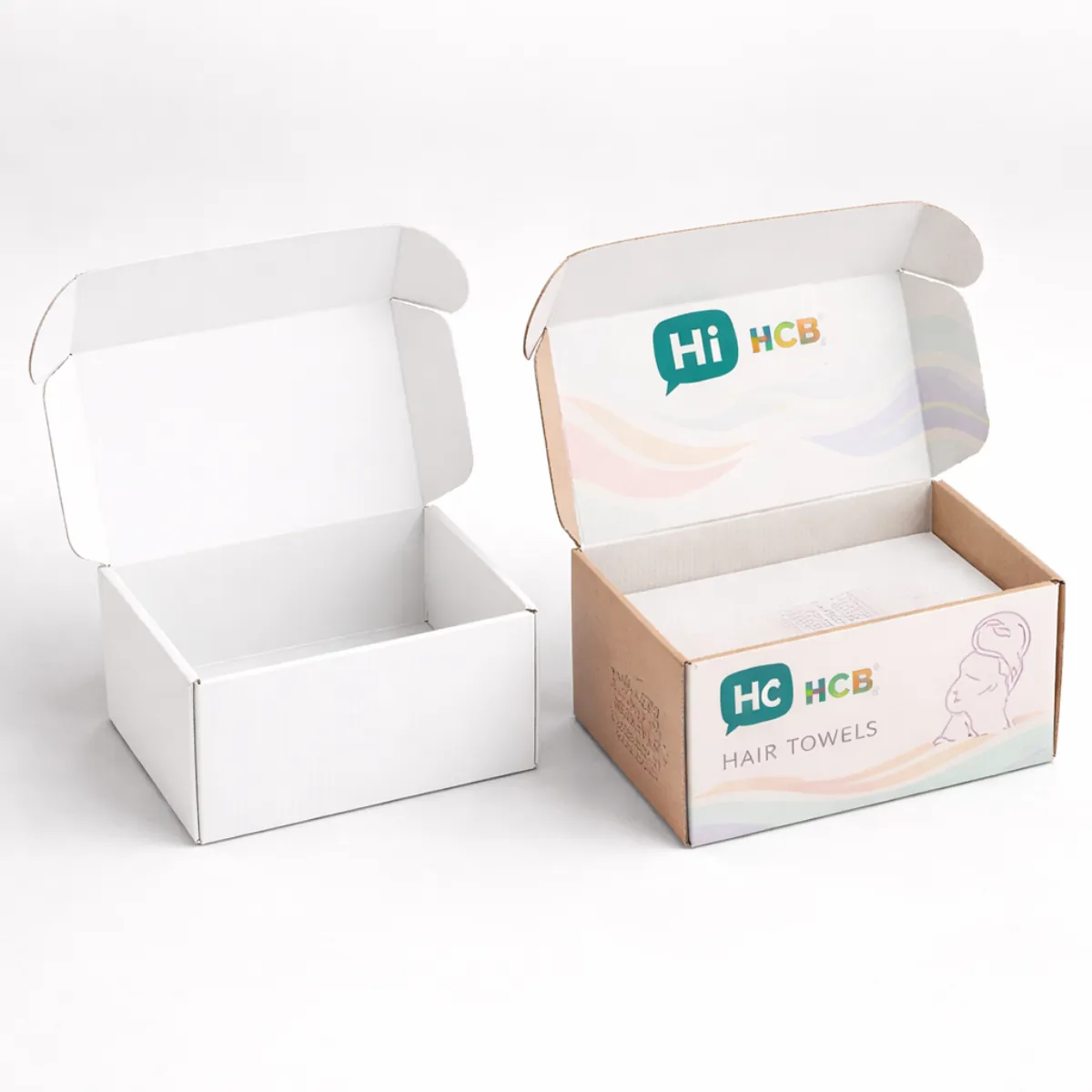 Two open cardboard mailing boxes- one plain white and one printed with a colourful towel brand- class=